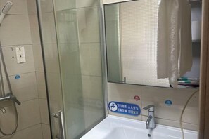 A bathroom with a glass shower enclosure, a bathtub, and a towel hanging on the wall.
