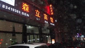 A building with signage in Chinese characters, a visible phone number, and a car parked in front. - Senli Hotel (Sanmen)