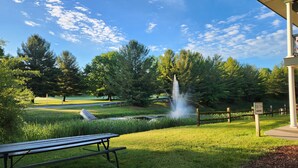 Een park met een fontein, een picknicktafel en een bord dat de richting naar een golfbaan aangeeft.