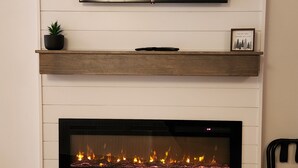 Een woonkamer met een flatscreen televisie boven een open haard.