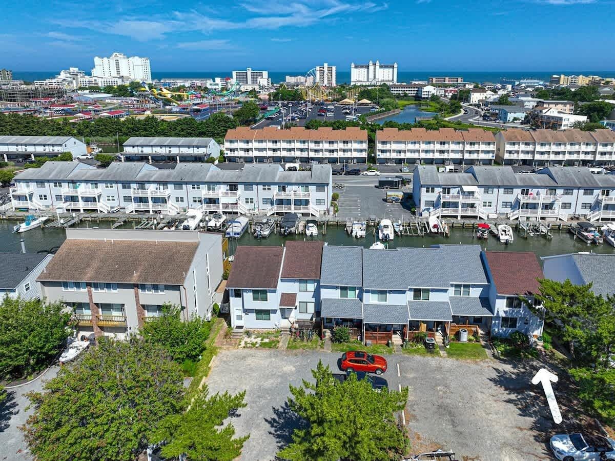 A marina with boats, a parking lot, and a row of multi-story buildings with balconies.