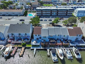A waterfront hotel with multiple balconies, a dock with boats, and a swimming pool. - Waterfront Getaway with Boat Slip (Ocean City)