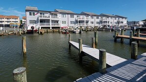 A marina with docked boats, wooden walkways, and a row of white buildings with balconies. - Waterfront Getaway with Boat Slip (Ocean City)