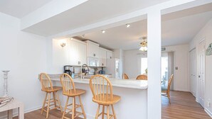 A modern kitchen with white cabinets, a central island with bar stools, and a visible microwave. - Waterfront Getaway with Boat Slip (Ocean City)