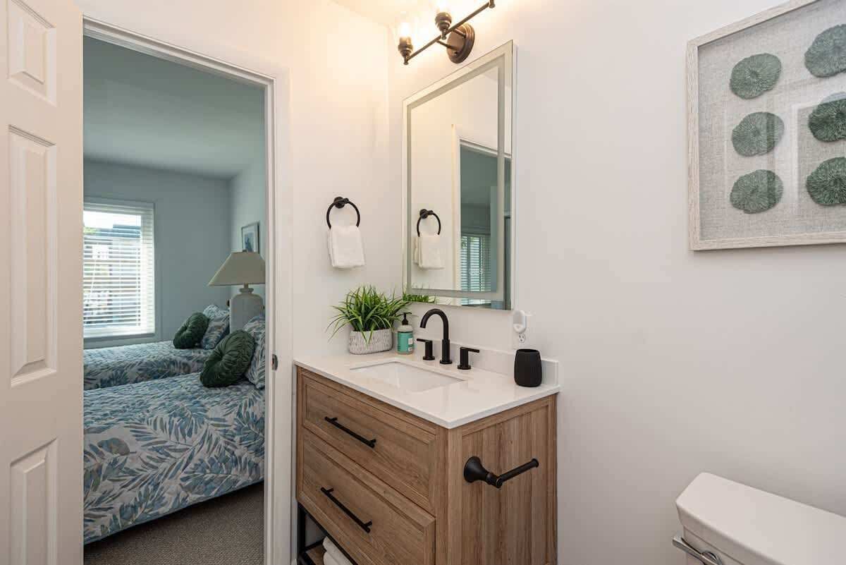 Ett badrum med ett handfat i trä, en vit tvättställ och en stor spegel.
