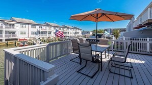 A deck with outdoor furniture, a flag, and a view of a marina with boats. - Waterfront Getaway with Boat Slip (Ocean City)