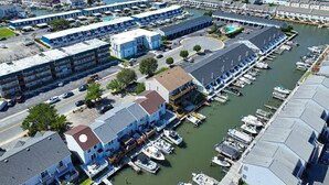 A marina with boats docked, a parking area, and buildings with balconies. - Waterfront Getaway with Boat Slip (Ocean City)