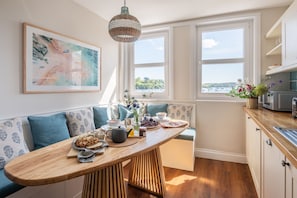 Een keuken met een houten tafel, een bank en uitzicht op zee.