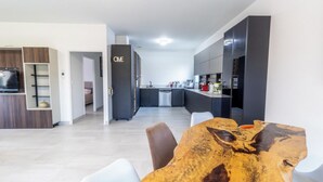Eine moderne Küche mit dunklen Schränken, ein Essbereich mit einem Holztisch und ein gut sichtbares Schild mit der Aufschrift 'ONE' an der Wand.