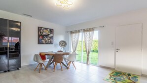 Ein stilvoller Essbereich mit Tisch und Stühlen, einem Gemälde an der Wand und Blick ins Freie durch große Fenster.