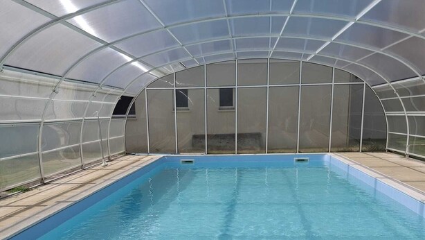 Ein Hallenschwimmbad mit Glasdach, klarem blauen Wasser und einem Poolbereich mit einer Wasserflasche und einer Schnorchelmaske.