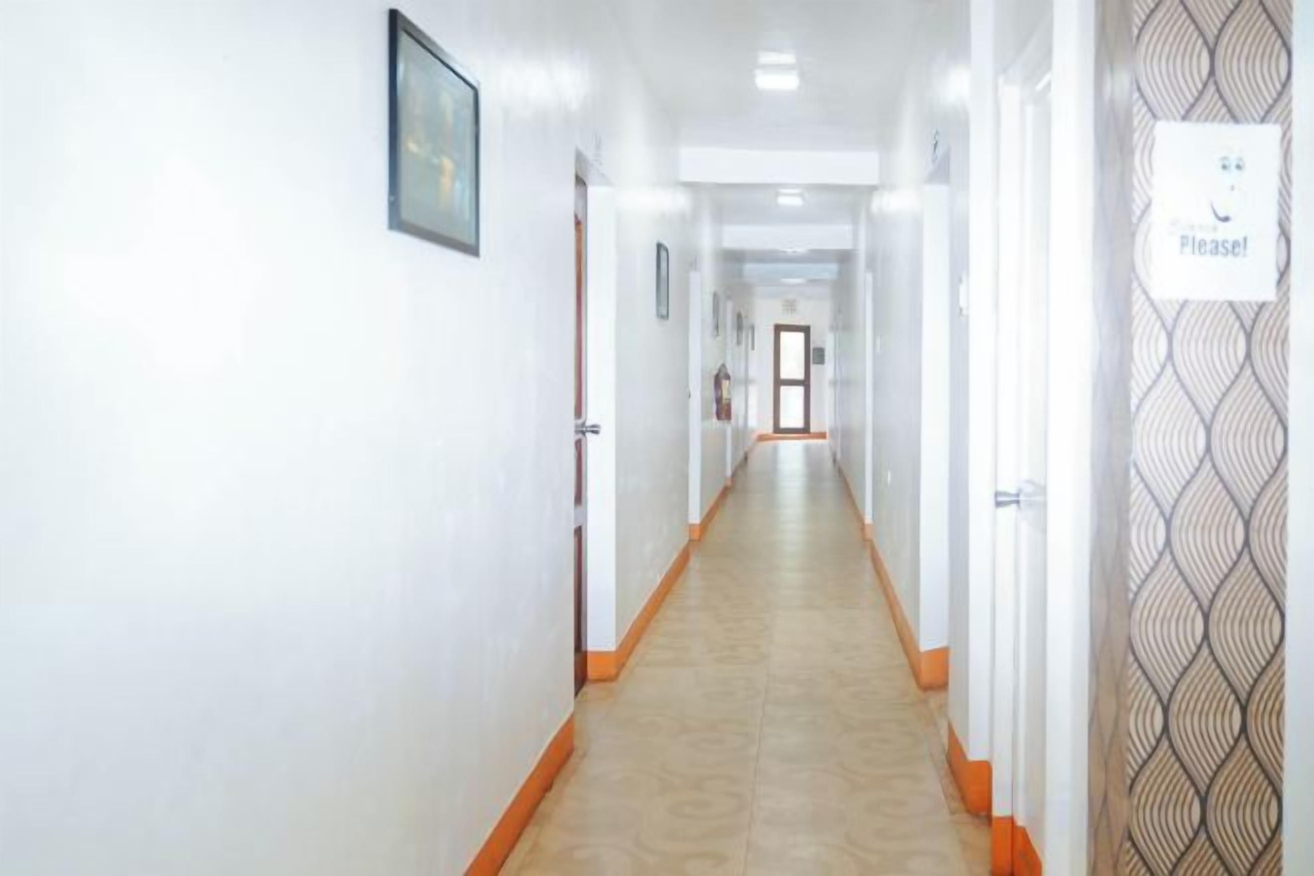 A hotel hallway with doors on both sides, a carpeted floor, and a patterned wall on the right.