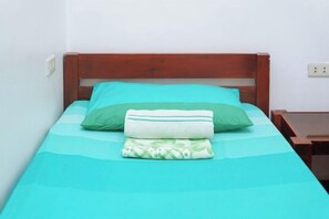 A single bed with a wooden headboard, a teal bedspread, and two pillows. - C Star Travellers Inn (Oslob)