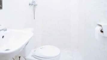 A bathroom with a white sink, toilet, and shower.