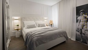A modern bedroom with a large bed, two bedside tables, a wall-mounted light, and a poster of a classical statue. - Premium apartment Ca' San Marco in a historic town (Labin)