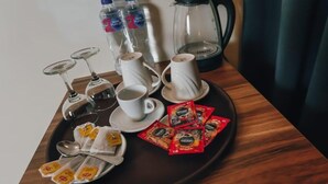 Un plateau avec des tasses à café, des verres à vin et des sachets de thé, posé sur une table en bois.