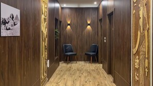 Un couloir aux murs en bois, avec deux chaises et un panneau décoratif.