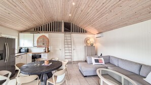 Una cocina moderna con estufa integrada, armarios blancos y techo de madera.
