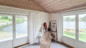 Una habitación con techo de madera y amplias ventanas con vistas a un lago.