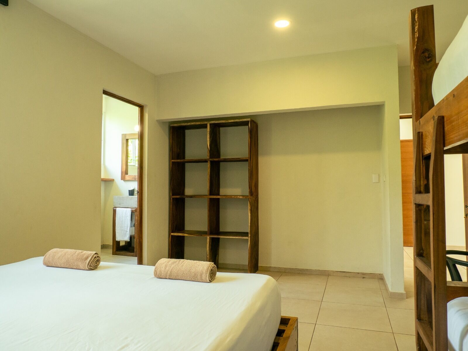 Un dormitorio con cama, un armario de madera y un baño visible a través de una puerta abierta.
