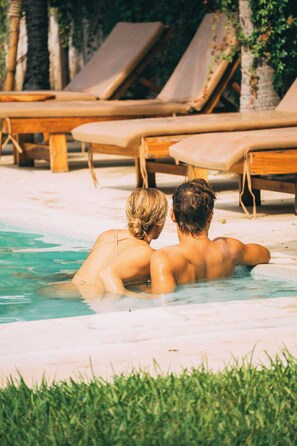 A couple in a swimming pool with lounge chairs and palm trees in the background. - Casaola Mizata (Teotepeque)