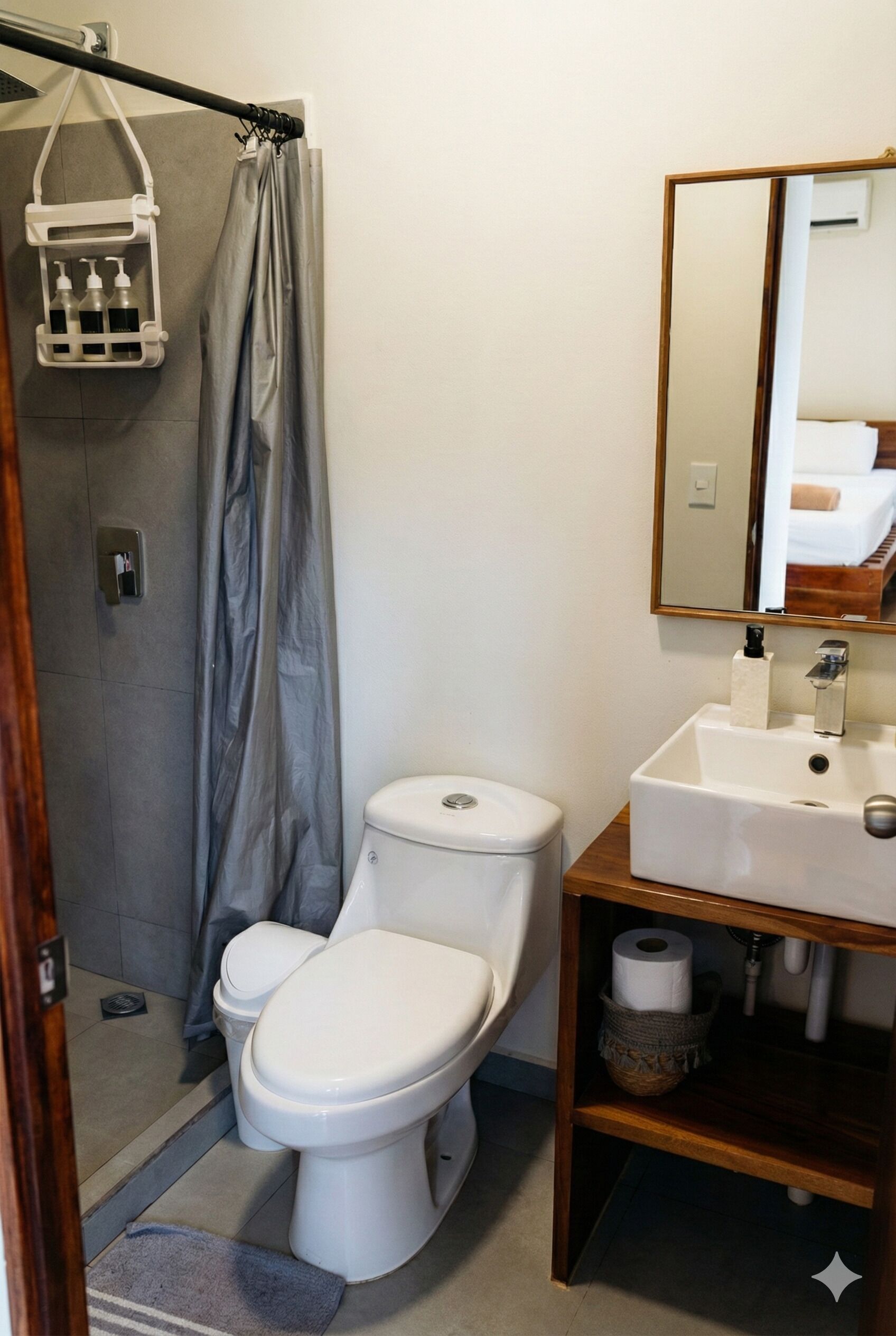 Baño con ducha, inodoro, lavabo y espejo.