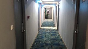 A hallway with a stone-patterned carpet, doors on both sides, and a framed picture on the wall.