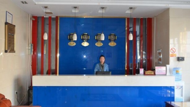 A reception desk with a blue and white color scheme, a person seated behind it, and a clock on the wall.