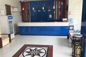 Zona de recepción con mostrador azul, refrigerador, dispensador de agua y un diseño de piso estampado.