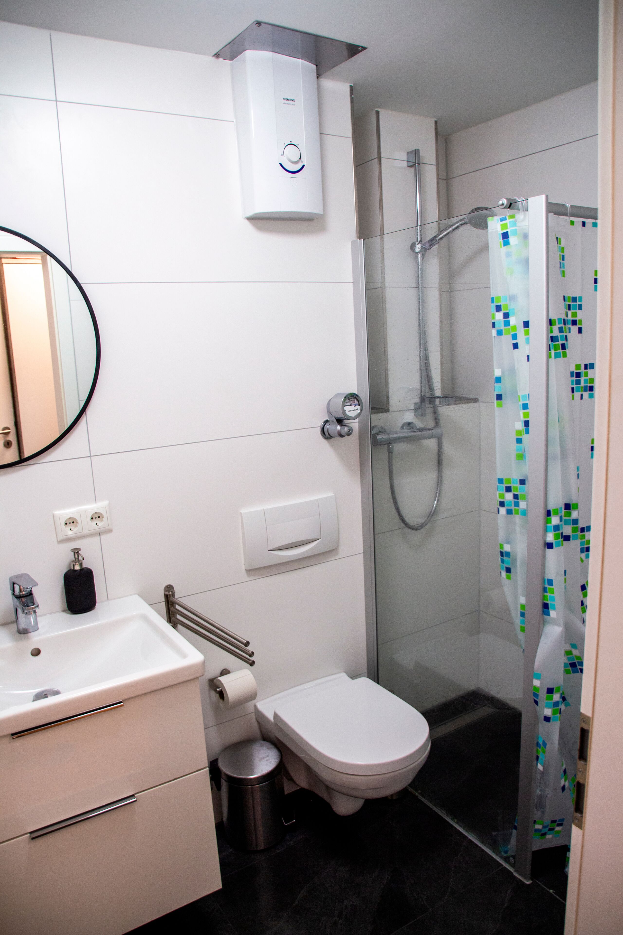 Een moderne badkamer met toilet, wastafel en douche.