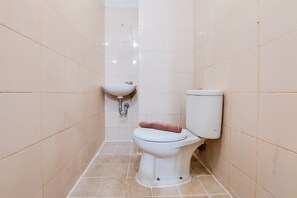 Bathroom features a toilet and sink, with beige tile walls and floor.