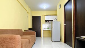 A compact living space with a sofa, a kitchenette, and a door. - Warm And Cozy 2Br Mutiara Bekasi Apartment (Bekasi)