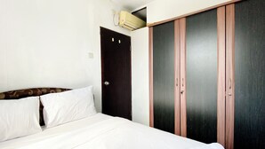 A hotel room with a bed, a wardrobe, and an air conditioning unit. - Warm And Cozy 2Br Mutiara Bekasi Apartment (Bekasi)