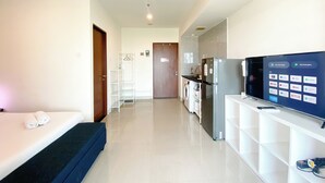 Una habitación de hotel moderna con cama, televisión, zona de cocina y estación de lavandería.