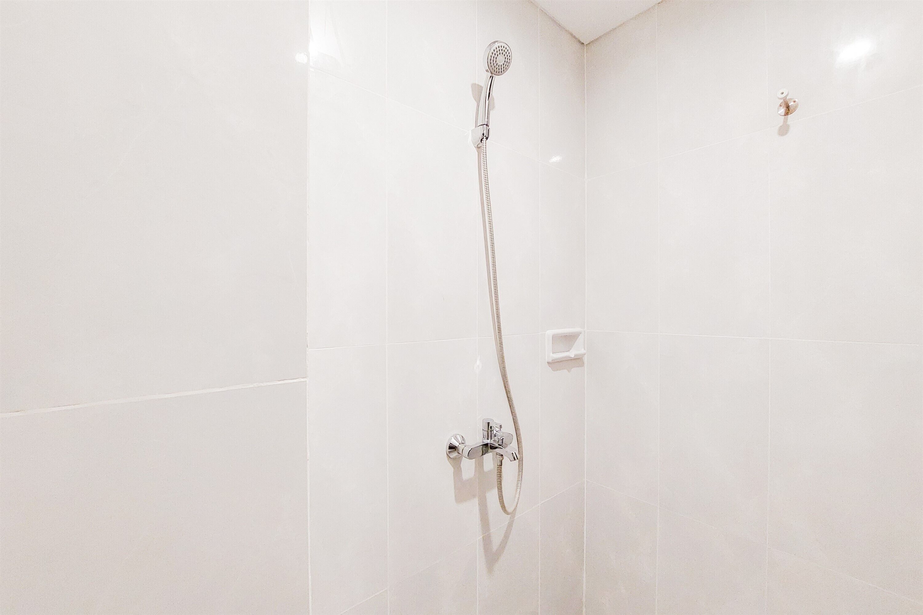 Une douche équipée d’un pommeau de douche à main et d’un robinet mural.