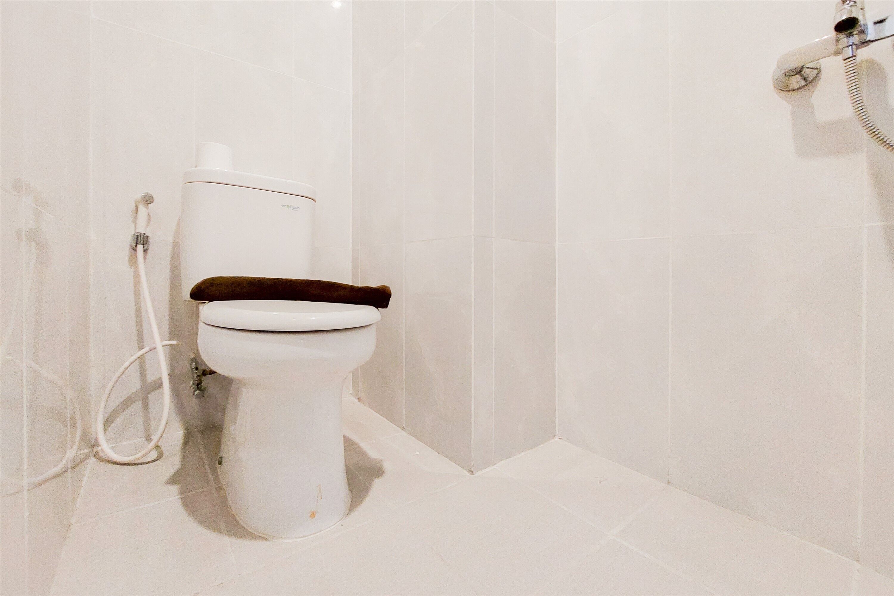 Egy fürdőszoba, amelyben WC, zuhanyzó és WC-papírtartó található.