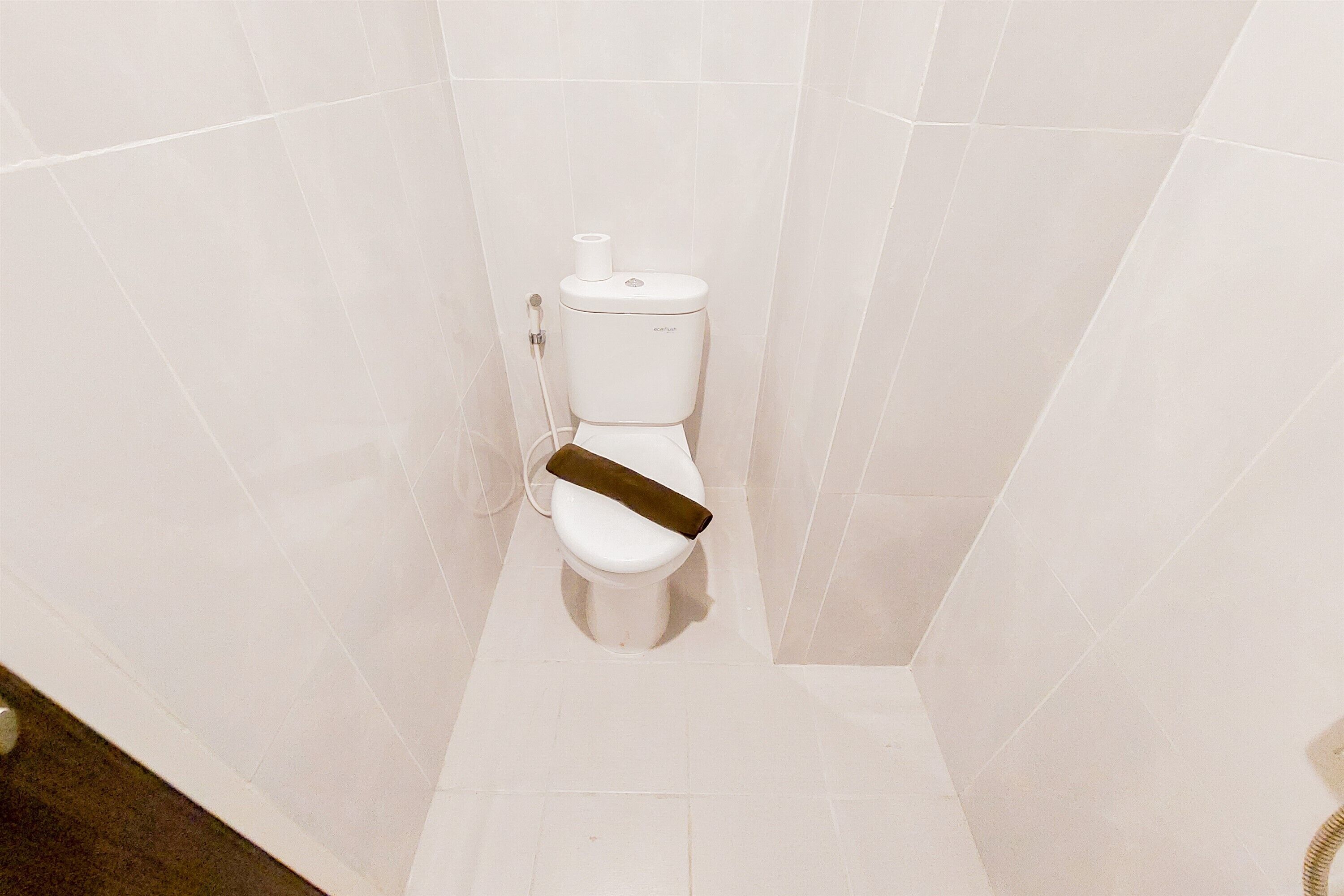 A white toilet in a bathroom with white tiles on the walls.