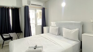 Una camera d'albergo con un letto, una sedia, un condizionatore d'aria e una porta.