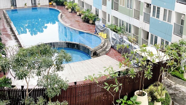 Un edificio residenziale a più piani con piscina e vegetazione circostante.