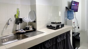 Una cucina con un lavello, un fornello, un dispenser d'acqua e una sveglia appesa al muro.