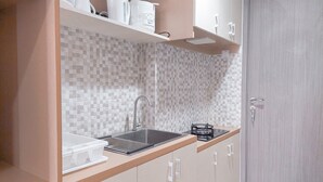 A modern kitchen with a tiled backsplash, a stainless steel sink, and wooden cabinets. - Simply Look And Comfort Studio Tamansari Bintaro Mansion Apartment (South Tangerang)