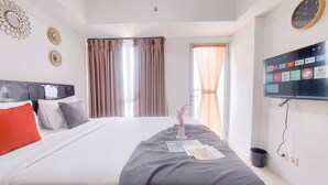 A hotel room with a bed, a TV, and curtains. - Simply Look And Comfort Studio Tamansari Bintaro Mansion Apartment (South Tangerang)