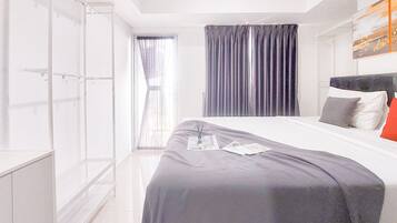 A modern hotel room with a large bed, a wardrobe, and a window with curtains.