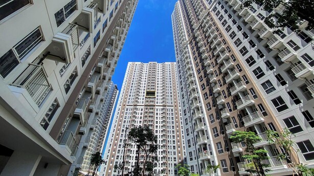 A high-rise residential building with multiple balconies, a clear blue sky, and surrounding greenery. - Good And Cozy Stay 2Br Tokyo Riverside Pik 2 Apartment (Teluknaga)