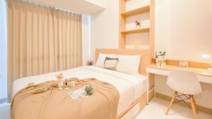 A neatly arranged hotel room with a bed, a desk, and a chair. - Good And Cozy Stay 2Br Tokyo Riverside Pik 2 Apartment (Teluknaga)