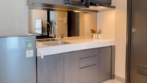 A modern kitchen with stainless steel appliances, a double sink, and a microwave above the stove. - Spacious 1Br At Tokyo Riverside Pik 2 Apartment (Teluknaga)