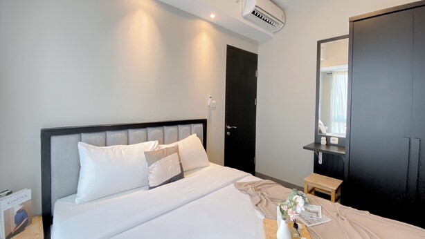 A hotel room with a bed, bedside table, and a mirror. - Spacious 1Br At Tokyo Riverside Pik 2 Apartment (Teluknaga)