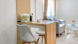 A modern living room with a dining area, a sofa, a coffee table, and a kitchen area with a rice cooker. - Comfort 2Br Apartment At Meikarta Cikarang (Cikarang)