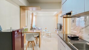 A modern kitchen with a marble countertop, stainless steel sink, and a dining area with a table and chairs. - Comfort 2Br Apartment At Meikarta Cikarang (Cikarang)