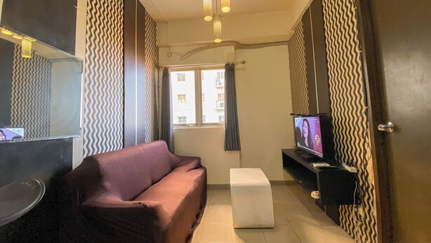 A modern living room with a sofa, a television, and a small table. - Nice 2Br At Apartment Suites @Metro (Bandung)